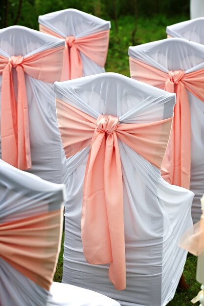 Decorated chairs for guests at a wedding in the garden.