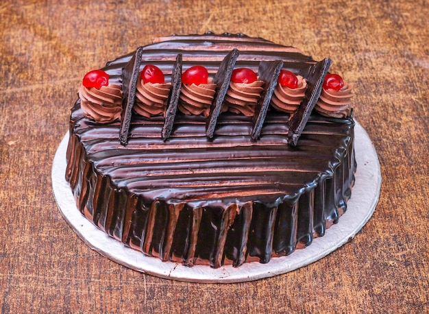 Decorated chocolate syrup cake on wooden background top view