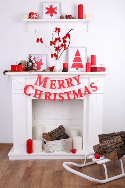 Decorated Christmas fireplace with inscription "Merry Christmas" on white wall surface