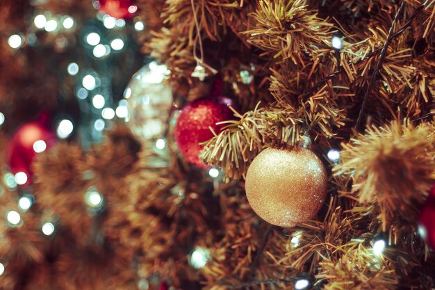 Decorated Christmas tree on blurred background. Christmas decoration. Hanging red balls on pine branches christmas tree garland and ornaments over abstract bokeh background with copy space