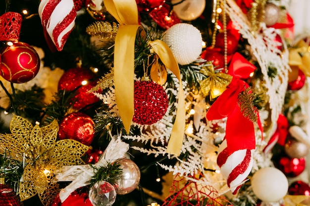 Decorated Christmas tree closeup. Red and golden balls and illuminated garland with flashlights.