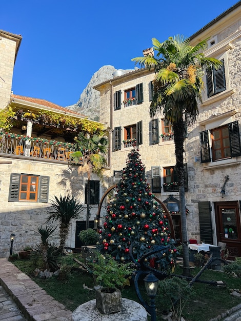 Decorated christmas tree in the courtyard of an old stone house among palm trees