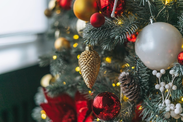 Albero di natale decorato in giocattoli dorati e rossi con lo sfondo strutturato del bokeh delle luci