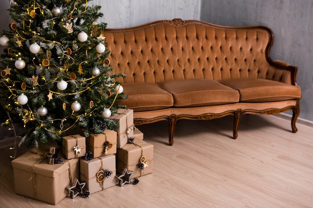 Decorated christmas tree, heap of gift boxes and copy space over wooden floor