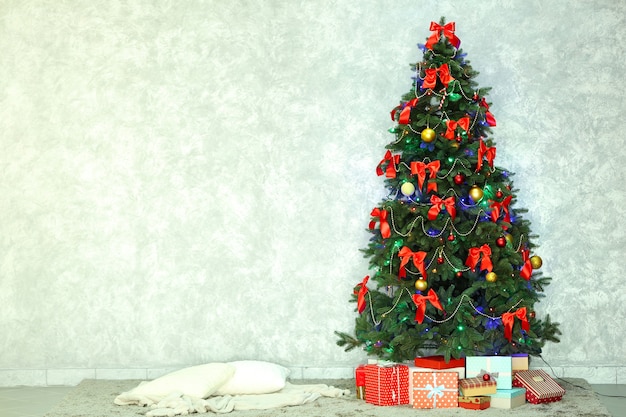 Decorated Christmas tree on light wall background