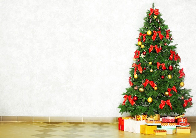 Decorated Christmas tree on light wall surface