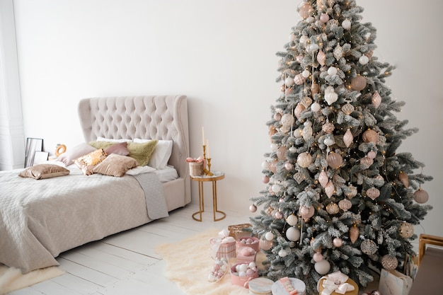 Decorated Christmas tree in room with bed.