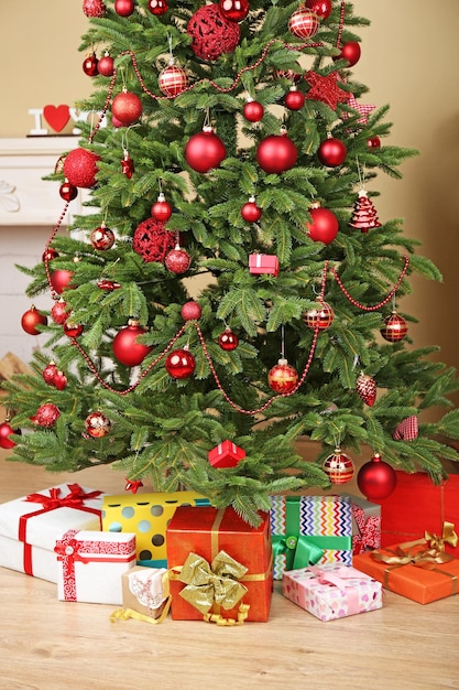 Decorated Christmas tree with gifts in room closeup