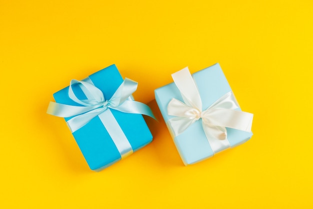 Decorated colored present on yellow background flatlay