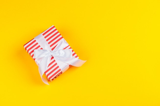 Decorated colored present on yellow background flatlay