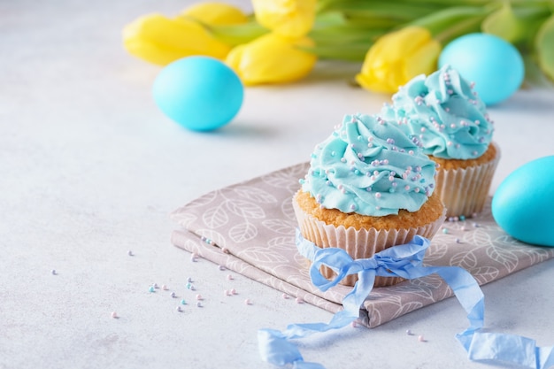 부활절을위한 크림, 파란 계란 및 튤립으로 장식 된 컵 케이크.