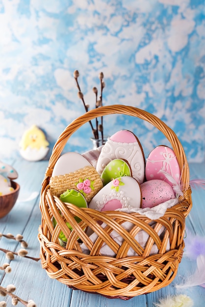 Decorated Easter Cookies in wooden basket on a blue wooden background