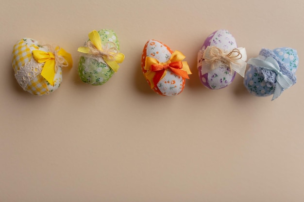 Украшенные тканью пасхальные яйца с цветными бантами на светлом фоне Пасхальный фон