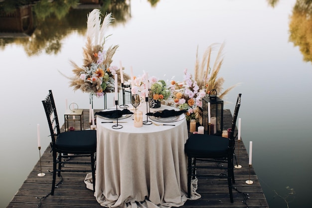 Decorated outdoor wedding table with flowers in boho style on lake beach