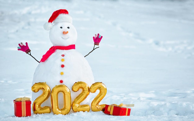 Decorated Snowman with figures of the upcoming new year and gifts at its base on sunny winter day