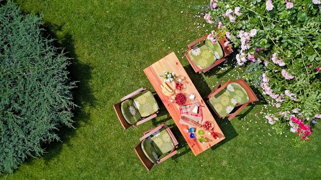 Tavolo decorato con fragole al formaggio e frutta in bella vista aerea dall'alto del roseto estivo