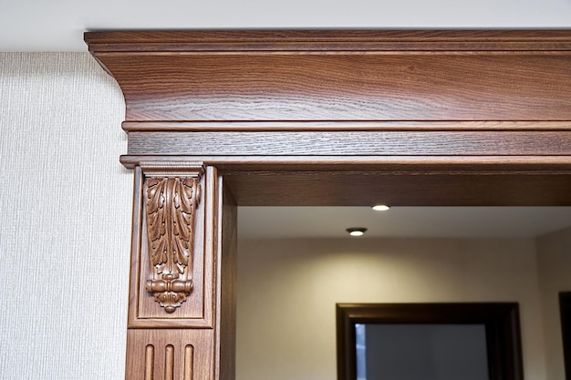 Decorated wooden doorway with carved furniture brackets and crown molding in classic style