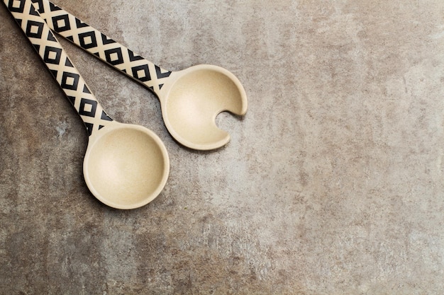 Decorated wooden salad server spoons on a marble table