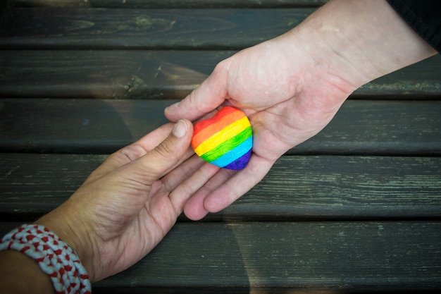 Decoratief hart met regenboogstrepen in mannelijke handen. lgbt-trotsvlag, homoseksuele liefde, mensenrechtenconcept.