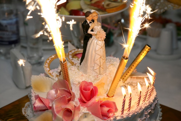 Decoratief paar pasgetrouwden met kaarsen op een bruidstaart