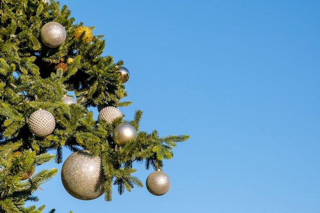 decoraties en garland op takken van faux kerstboom buiten op een blauwe hemel op zonnige zomerdag.
