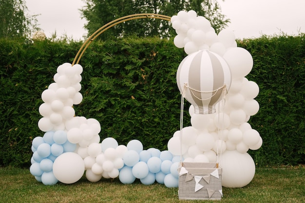 Decoraties voor vakantiefeest Veel ballonnen blauwe en witte kleuren Ronde fotozone met ballen naast een bal met een mand voor een kind