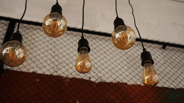 Decoratieve antieke edison-stijl lichte wolfraamlampen tegen de achtergrond van de muur met zwart gaas