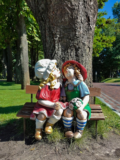 Decoratieve beeldjes van twee kinderen in het park zittend onder een boom en knuffelen