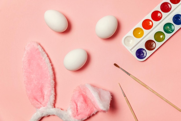 Decoratieve eieren kleurrijke verf en konijnenoren harige kostuum speelgoed geïsoleerd op trendy roze achtergrond