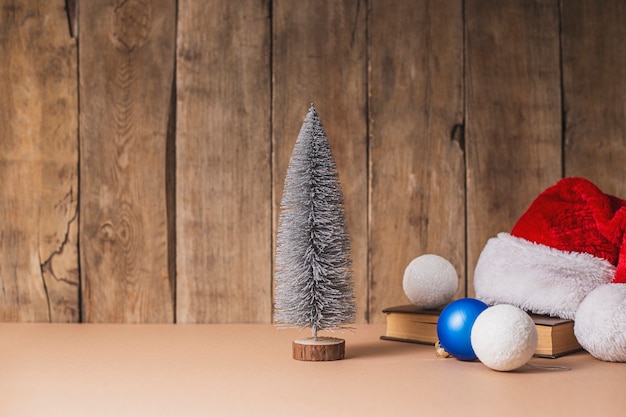 Decoratieve kerstboom, kerstversiering en kerstman hoed op een houten achtergrond.