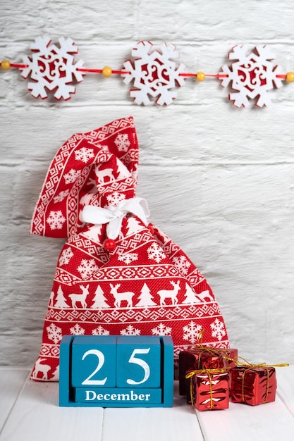 Decoratieve kerstcadeaudozen rode geschenkzak en blauwe eeuwigdurende kalender op witte bakstenen muur