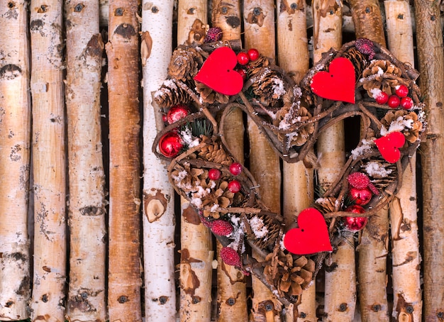 Decoratieve krans in de vorm van harten van kegels en twijgen op houten spijlen