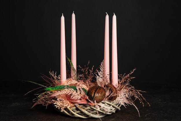 Foto decoratieve krans van vier roze adventkaarsen in een adventkrans decoratie op een donkere achtergrond in een bloemen stijl traditie voor kerstmis festive stilleven