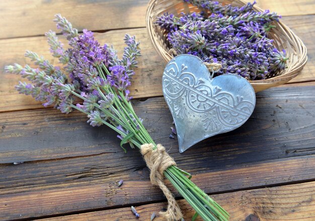 Decoratieve metalen hart onder bloemen van lavendel op houten achtergrond