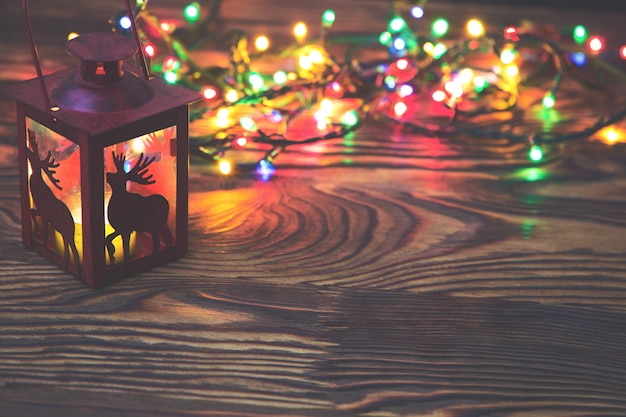 Decoratieve rode metalen lantaarn met een hert knipsel verlicht door een gloeiende kaars met kerstlicht en copyspace voor nieuwjaar of kerstmis