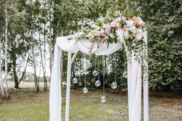 自然の中での結婚式のために花と布でアーチを飾る