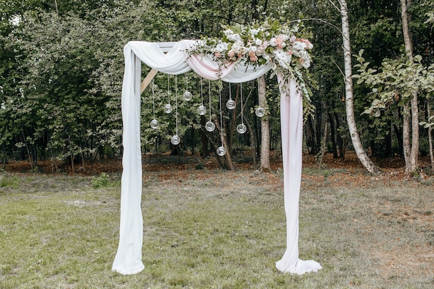自然の中での結婚式のために花と布でアーチを飾る