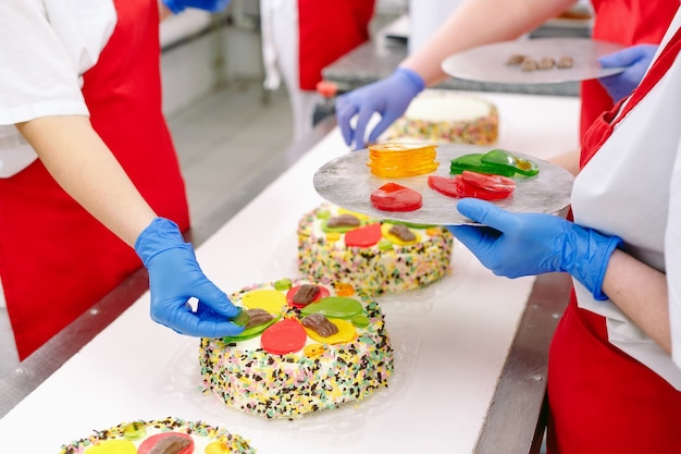 Decorating cakes on the conveyor of a confectionery factory