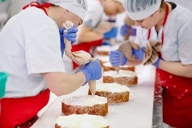 Decorating cakes on the conveyor of a confectionery factory