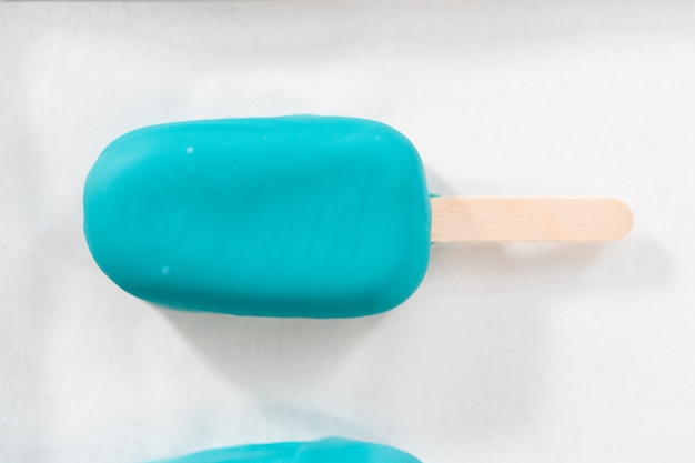 Decorating cakesicles with drizzled chocolate, chocolate mermaid tails, and seashells