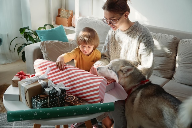 Decorating Christmas gifts family mother child and pet dog wrapping Christmas gift box together