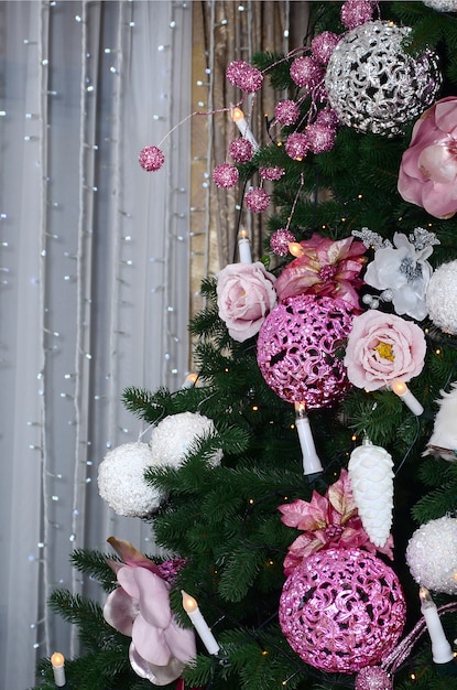 Decorating Christmas tree close up. Decoration bulb, fir tree, pink x-mas toys and lights