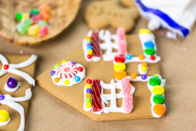 Decorating gingerbread house with royal icing and colorful candies.