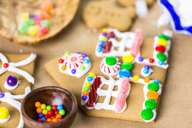 Decorating gingerbread house with royal icing and colorful candies.