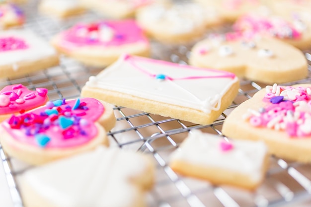 발렌타인 데이를 위해 왕실 장식과 분홍색 뿌리로 하트 모양의 설탕 쿠키를 장식하세요.