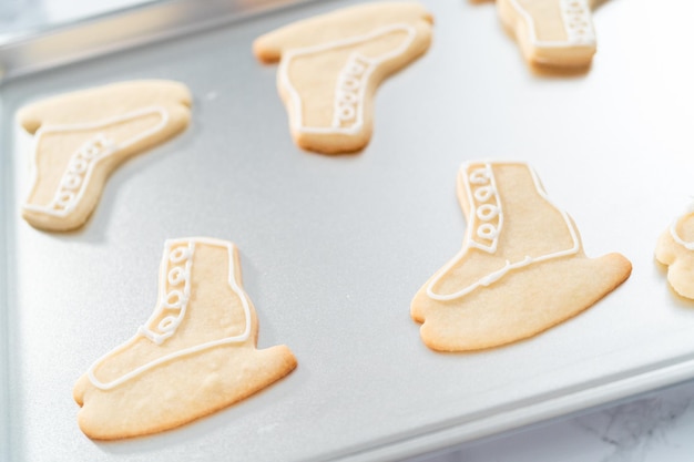 Photo decorating sugar cookies shaped as figure skates with royal icing.