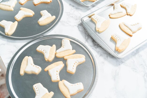 Decorating sugar cookies shaped as figure skates with royal icing.