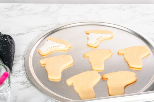 Decorating sugar cookies shaped as figure skates with royal icing.