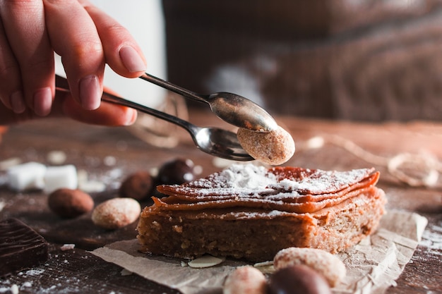 Decorating turkish dessert with nut closeup. Side view on confectioner hand putting almond on baklava, free space.