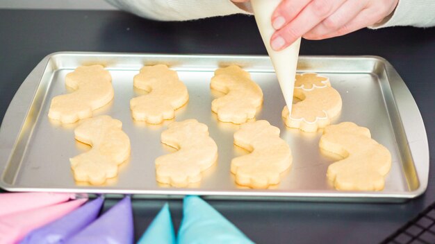 Decorating unicorn sugar cookies with multi-color royal icing.